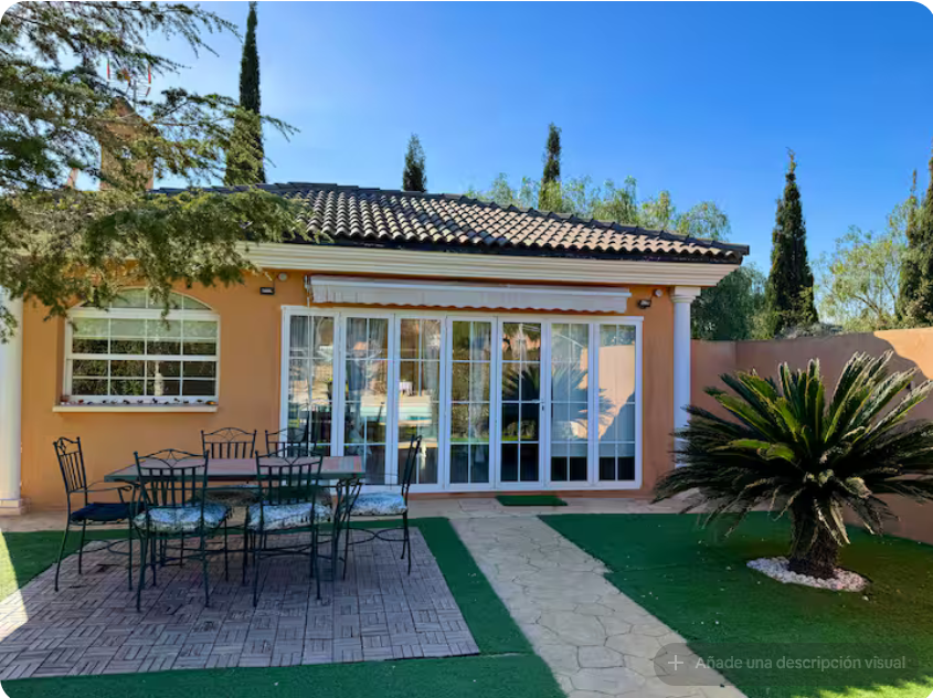 Fachada de la casa con terraza y mesa exterior